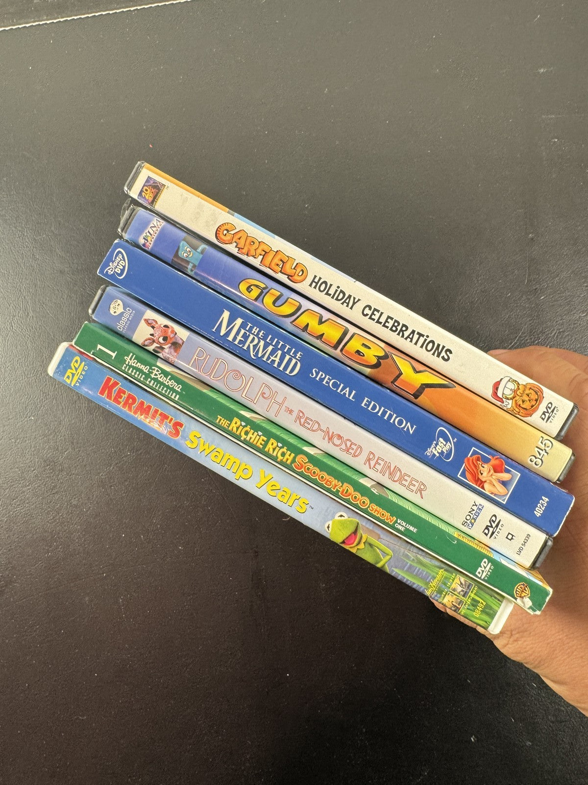 Collection of 6 family animation DVDs including Disney's The Little Mermaid, Scooby-Doo, and Garfield in cases.