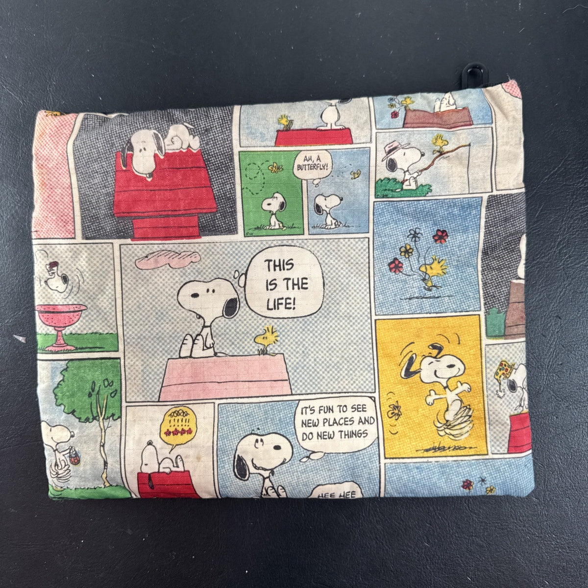 LeSportsac x Peanuts Snoopy vintage comic strip cosmetic pouch with top zip and black trim.