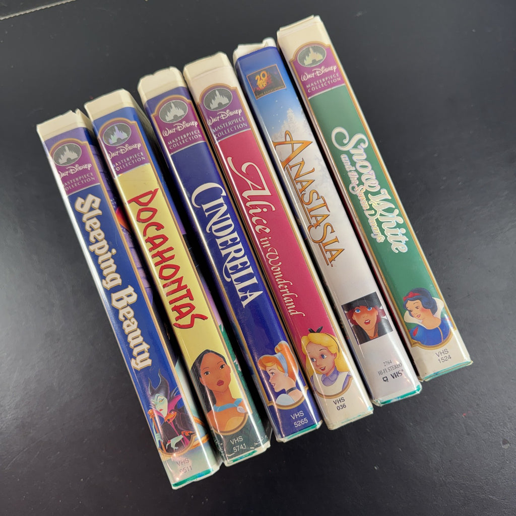 Set of 6 vintage Disney animated VHS tapes in original white clamshell cases including Cinderella and Sleeping Beauty.