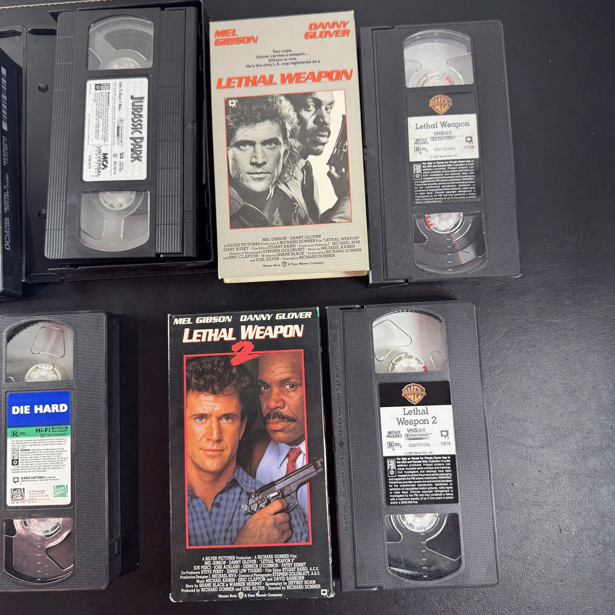 Lot of 5 classic action movie VHS tapes including Jurassic Park, Die Hard, and Lethal Weapon 1-3.