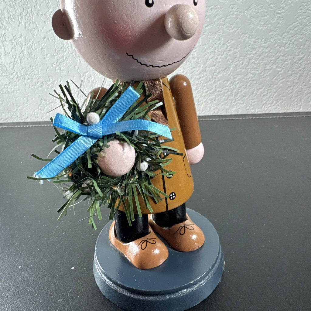 8-inch wooden Peanuts holiday nutcracker holding a Christmas wreath