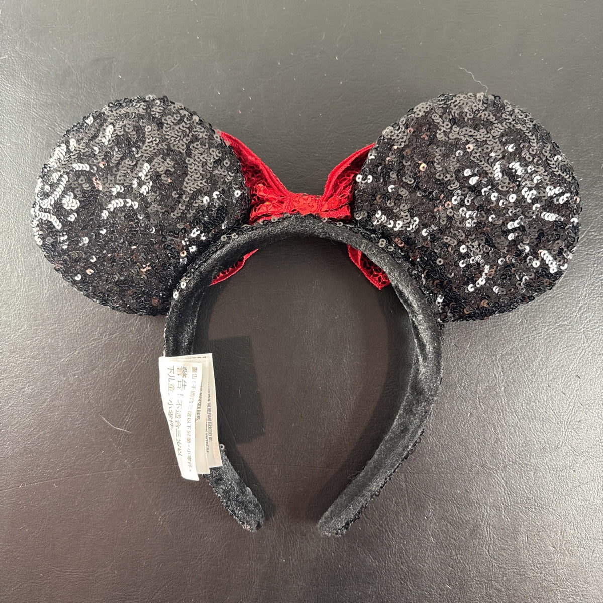 Disney Parks Minnie Mouse ears headband featuring a red sequined bow with gold accents.