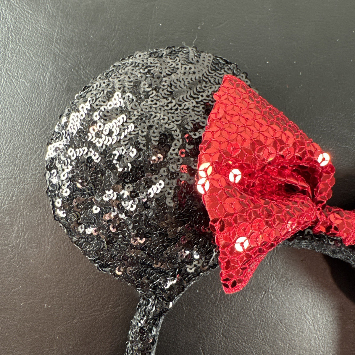 Disney Parks Minnie Mouse ears headband featuring a red sequined bow with gold accents.