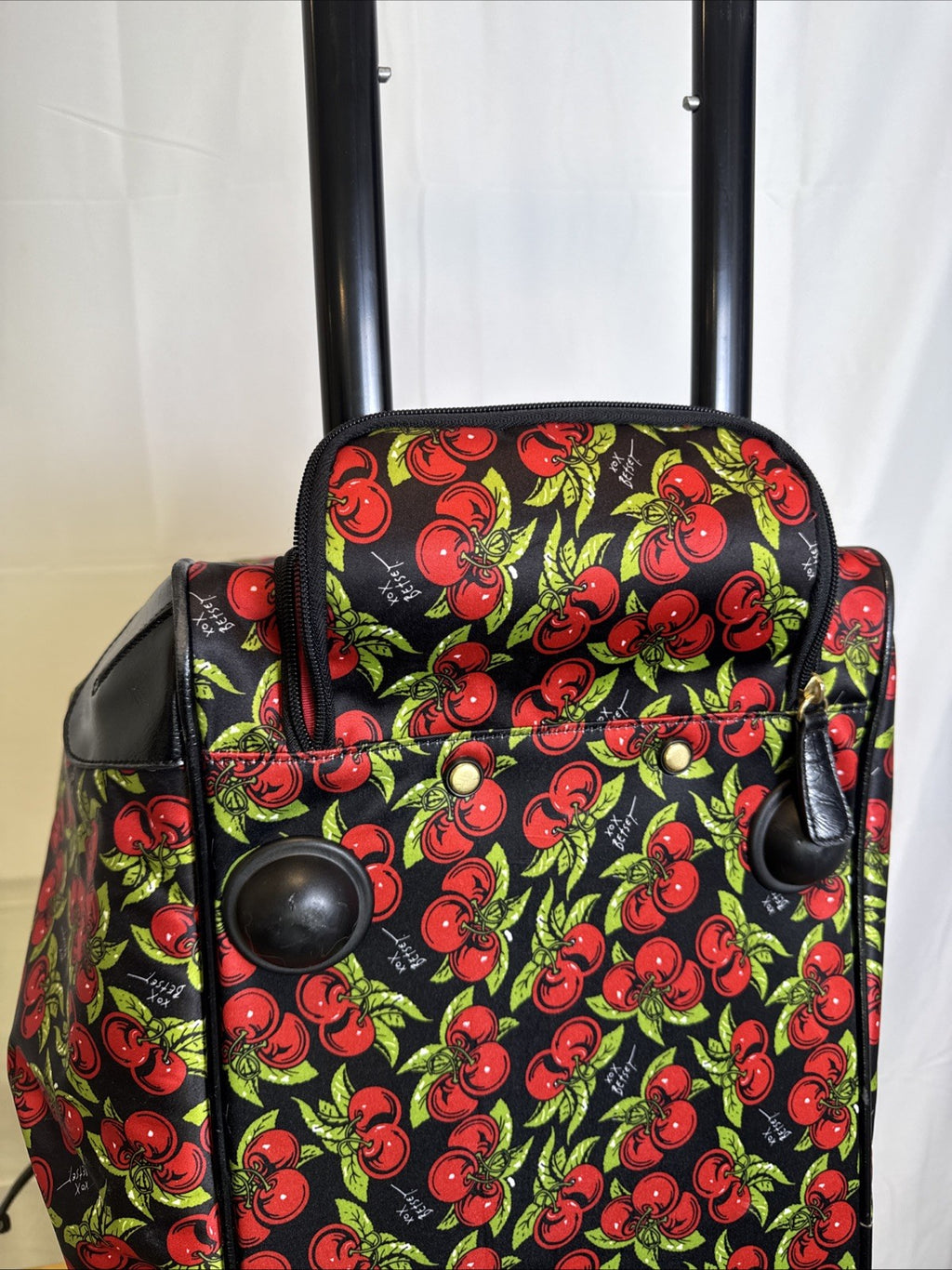 Betsey Johnson black rolling weekender duffel bag featuring a red cherry print and telescoping handle.