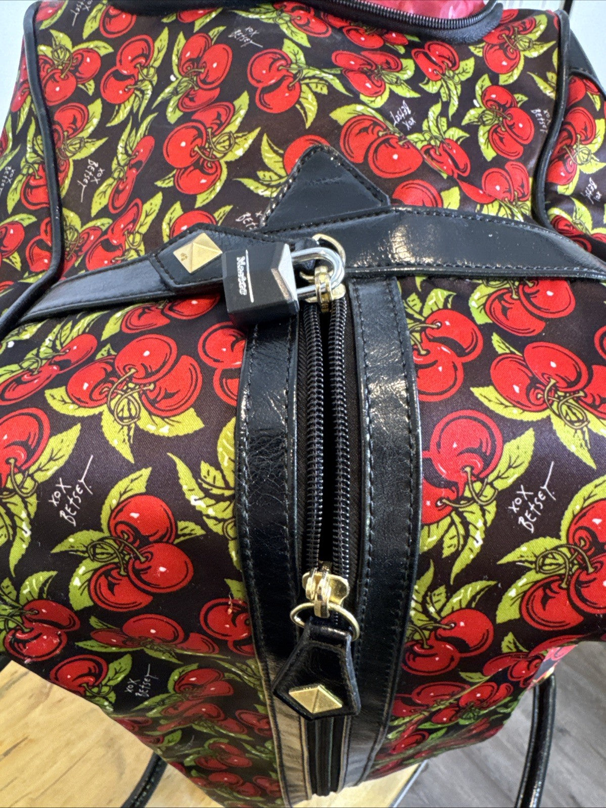 Betsey Johnson black rolling weekender duffel bag featuring a red cherry print and telescoping handle.