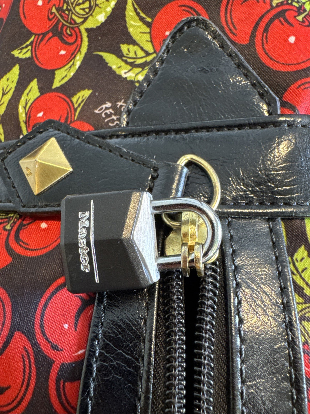 Betsey Johnson black rolling weekender duffel bag featuring a red cherry print and telescoping handle.