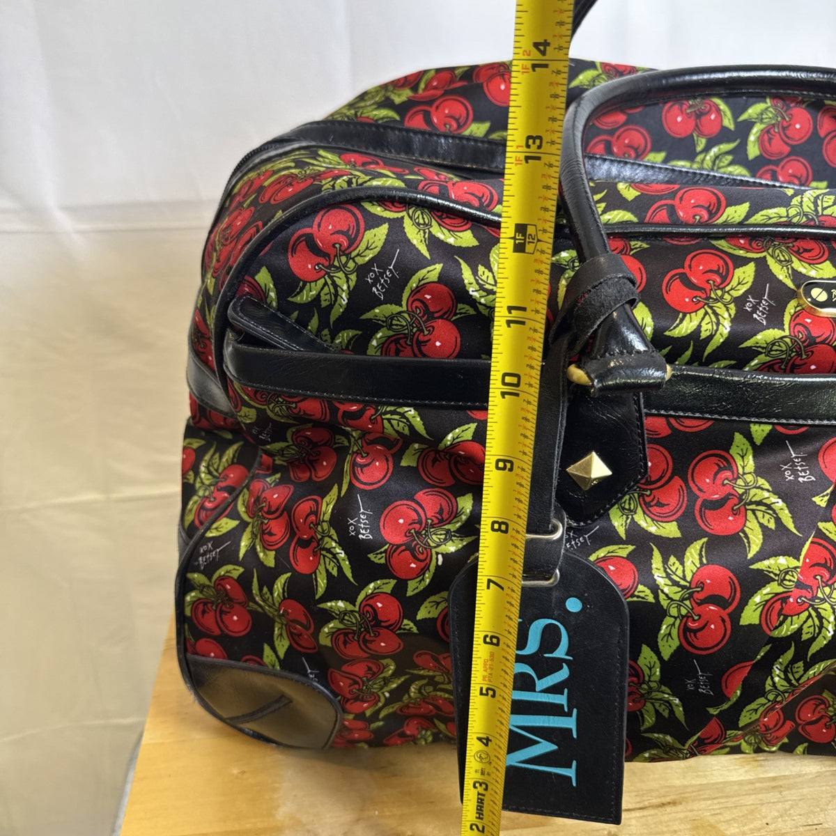 Betsey Johnson black rolling weekender duffel bag featuring a red cherry print and telescoping handle.