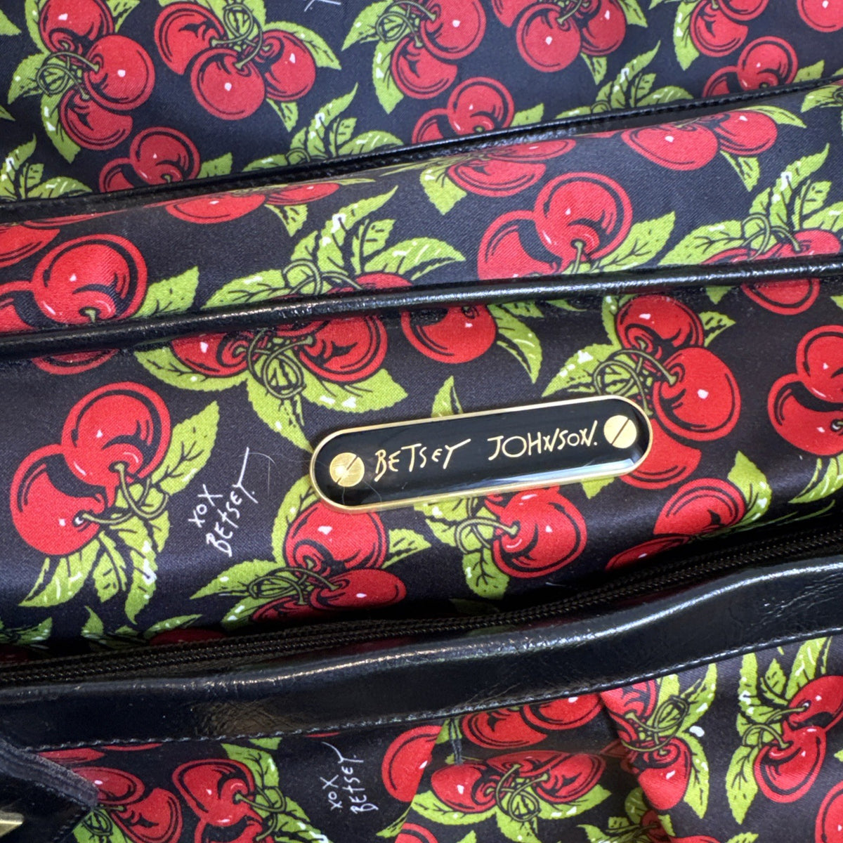 Betsey Johnson black rolling weekender duffel bag featuring a red cherry print and telescoping handle.