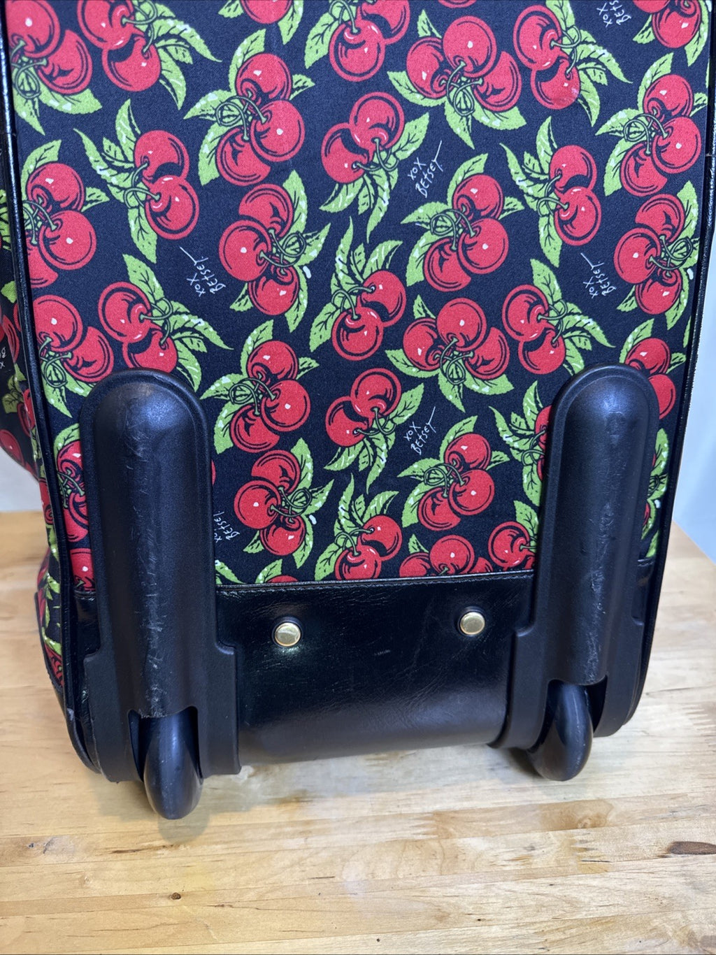 Betsey Johnson black rolling weekender duffel bag featuring a red cherry print and telescoping handle.