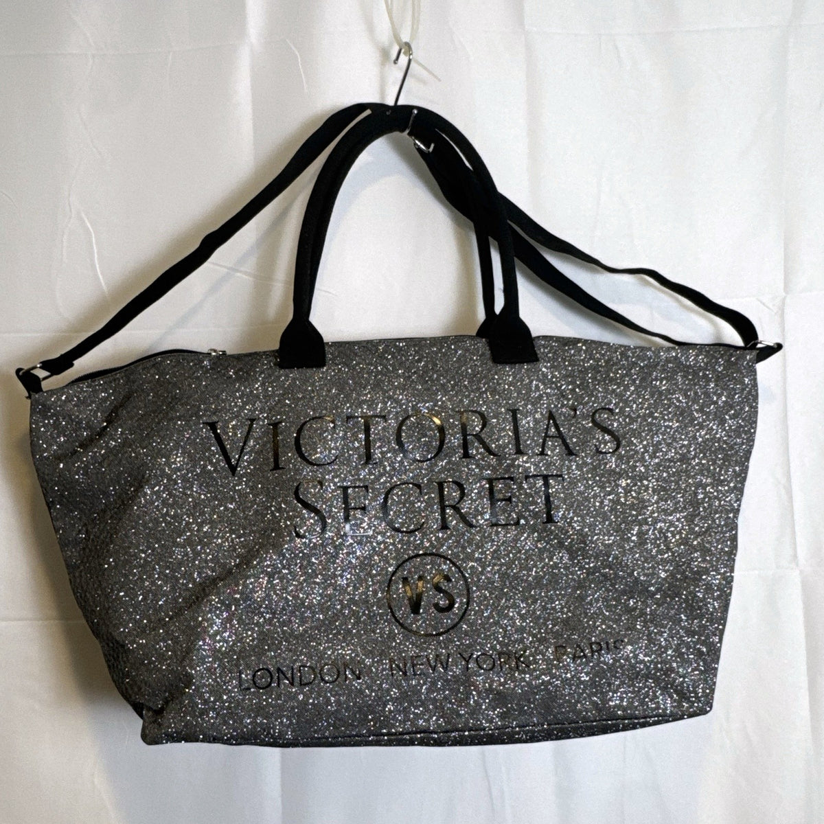 Victoria's Secret oversized silver glitter weekender tote bag with London New York Paris graphic and black canvas handles.
