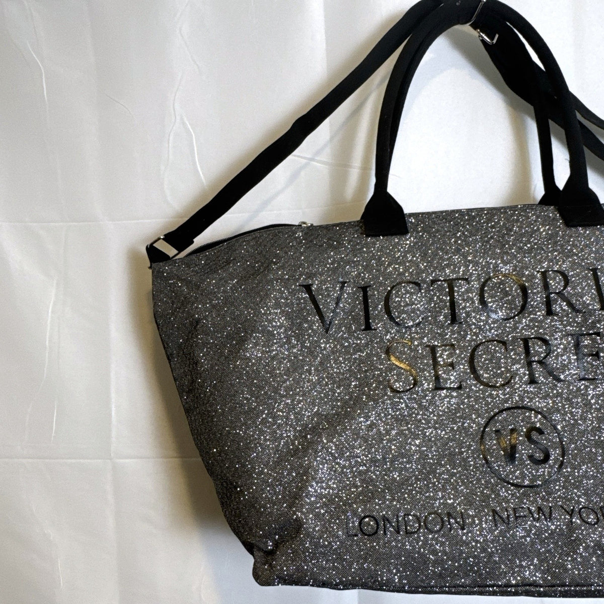 Victoria's Secret oversized silver glitter weekender tote bag with London New York Paris graphic and black canvas handles.