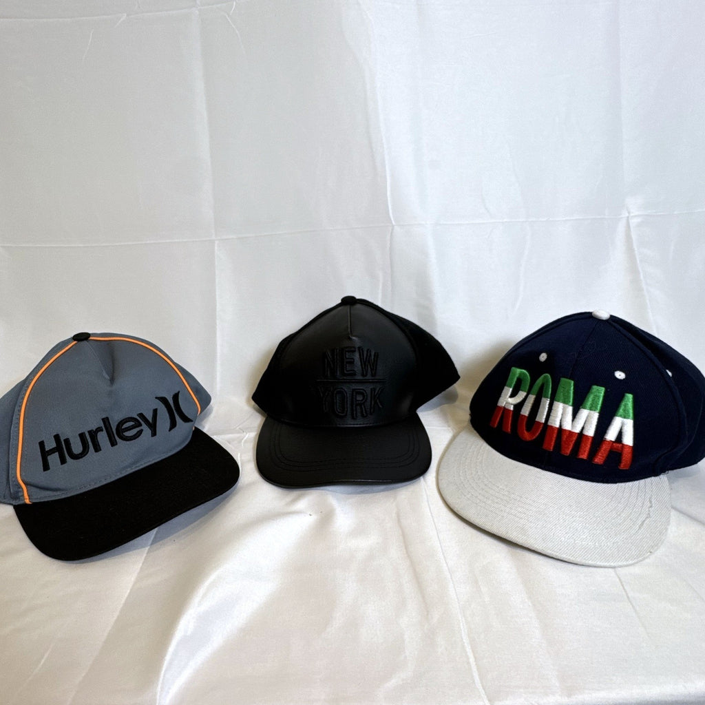 Set of 3 snapback hats including a grey Hurley youth cap, black H&M faux leather hat, and navy blue ROMA cap.