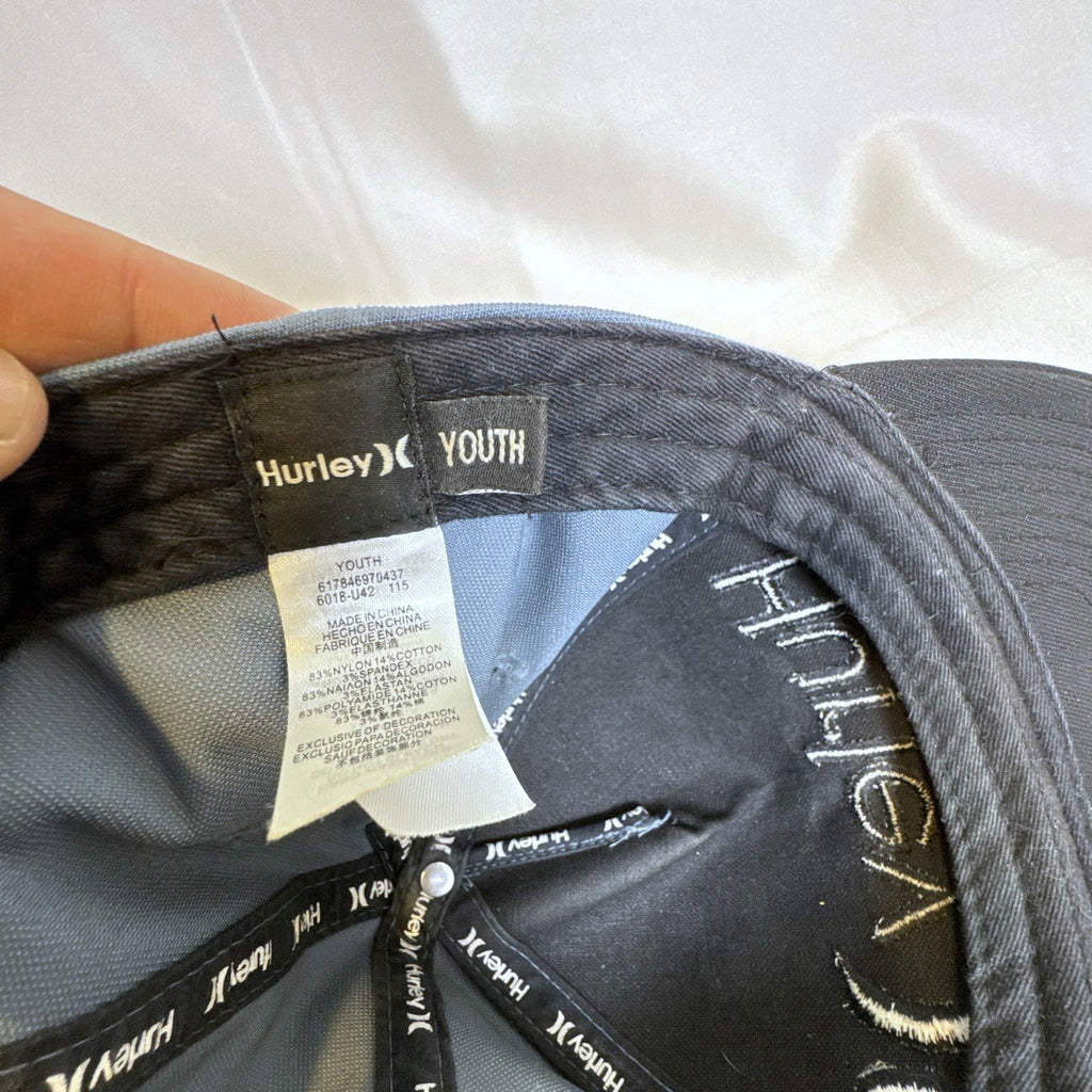 Set of 3 snapback hats including a grey Hurley youth cap, black H&M faux leather hat, and navy blue ROMA cap.