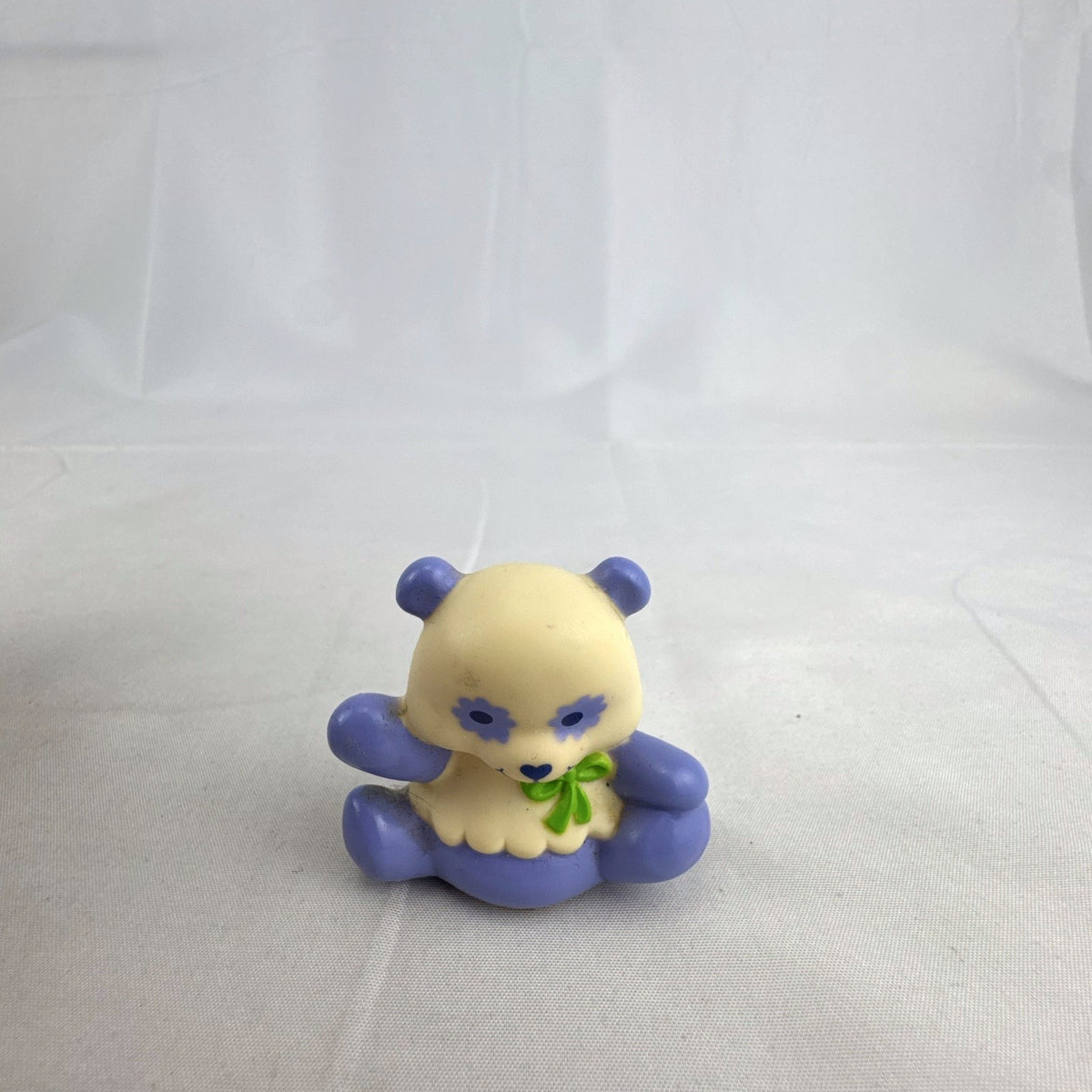 Vintage miniature purple and cream PVC vinyl panda bear figurine with green bow and flower-shaped eyes