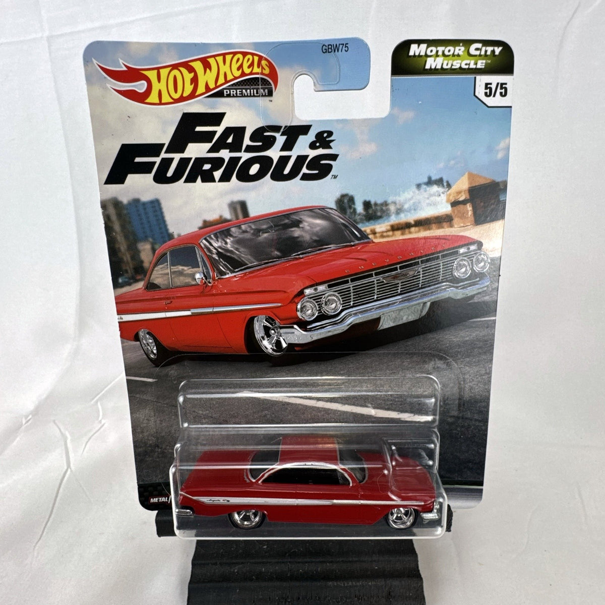 Hot Wheels Fast & Furious 1961 Chevrolet Impala 1:64 diecast car in gloss red with Real Riders tires in packaging.