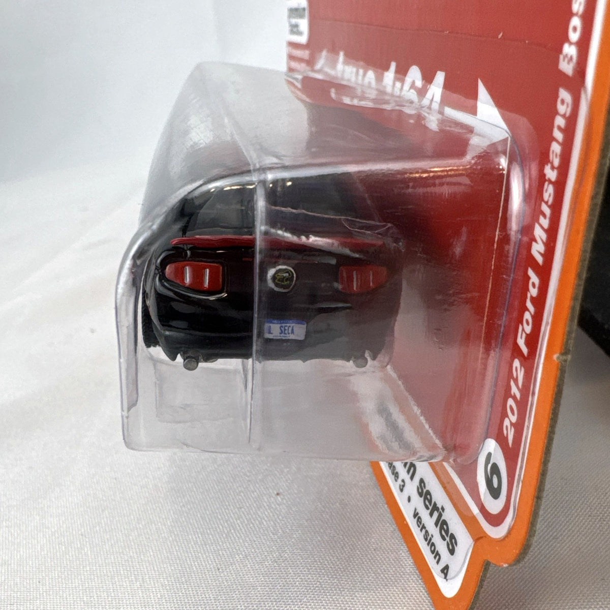 Auto World 1:64 scale 2012 Ford Mustang Boss 302 Laguna Seca diecast car in black with red accents in original packaging