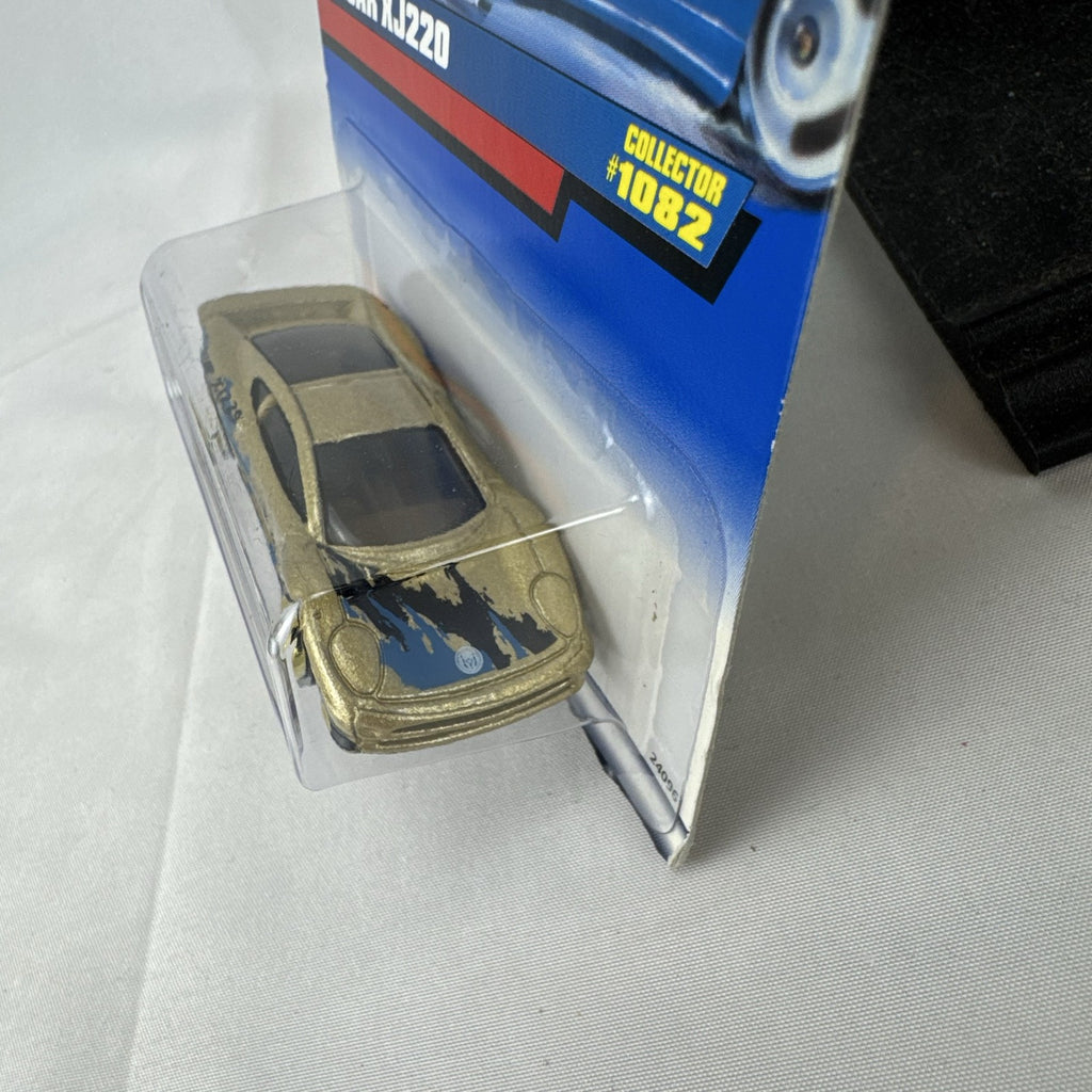 Hot Wheels 1:64 scale Jaguar XJ220 diecast car in metallic gold with 3-spoke wheels on unopened original card.