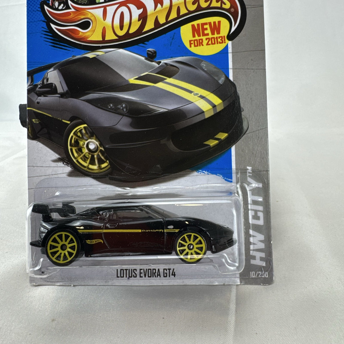 Hot Wheels 1:64 scale Lotus Evora GT4 diecast car in black with yellow stripes, factory sealed on original card