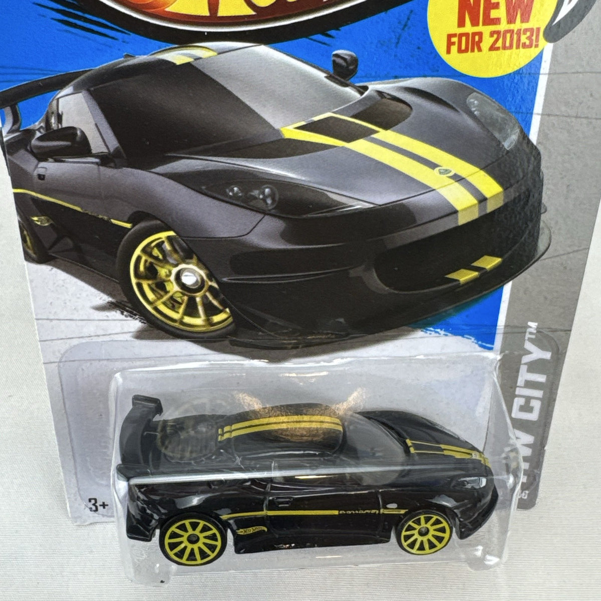 Hot Wheels 1:64 scale Lotus Evora GT4 diecast car in black with yellow stripes, factory sealed on original card