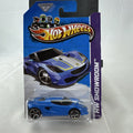 Blue Hot Wheels 1:64 scale Lotus M250 diecast car with white and yellow racing stripes sealed in original 2013 packaging.