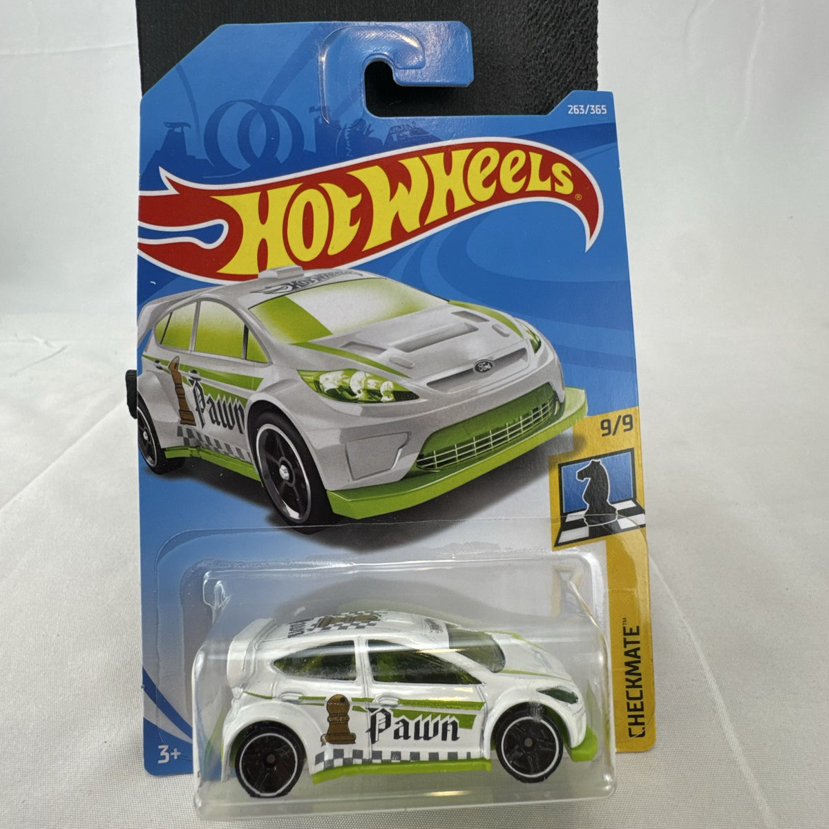 Hot Wheels 1:64 scale 2012 Ford Fiesta diecast car in white with green Pawn Checkmate graphics, sealed on card.