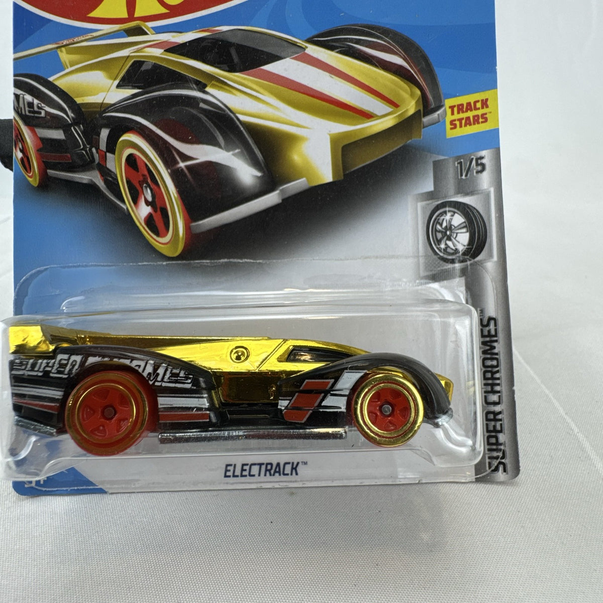 Factory sealed Hot Wheels ElecTrack 1:64 diecast car in gold chrome with red and white racing stripes on original card.