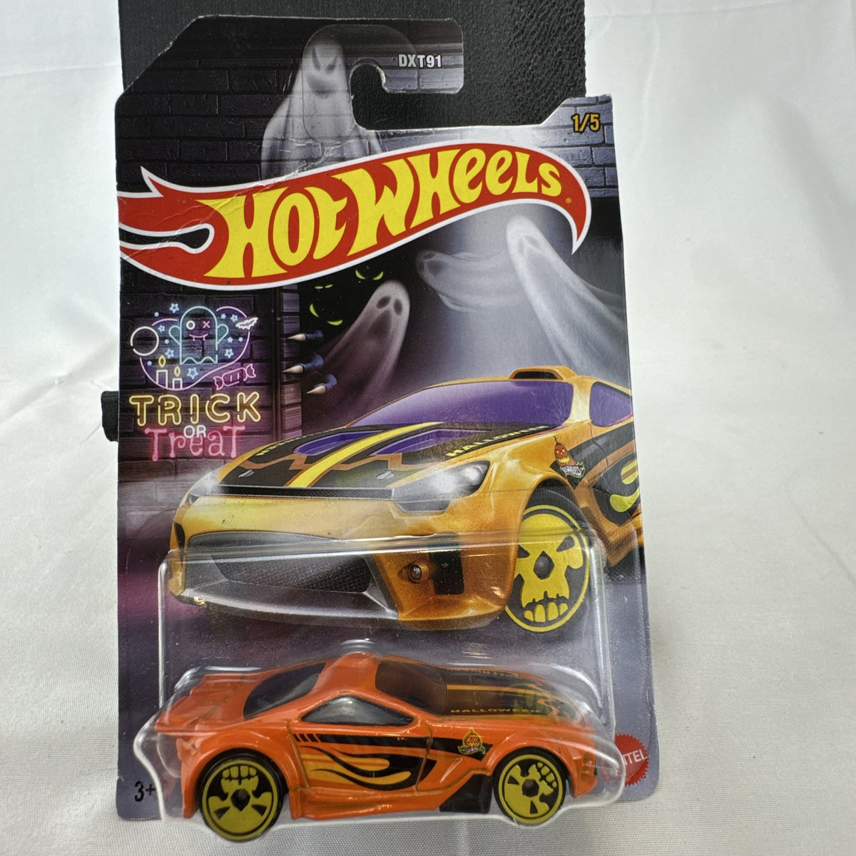 Hot Wheels 1:64 scale Scorcher diecast car in orange with Halloween graphics and yellow skull rims in sealed packaging.