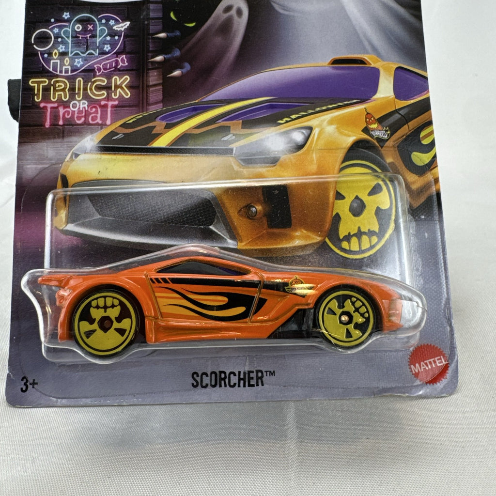 Hot Wheels 1:64 scale Scorcher diecast car in orange with Halloween graphics and yellow skull rims in sealed packaging.