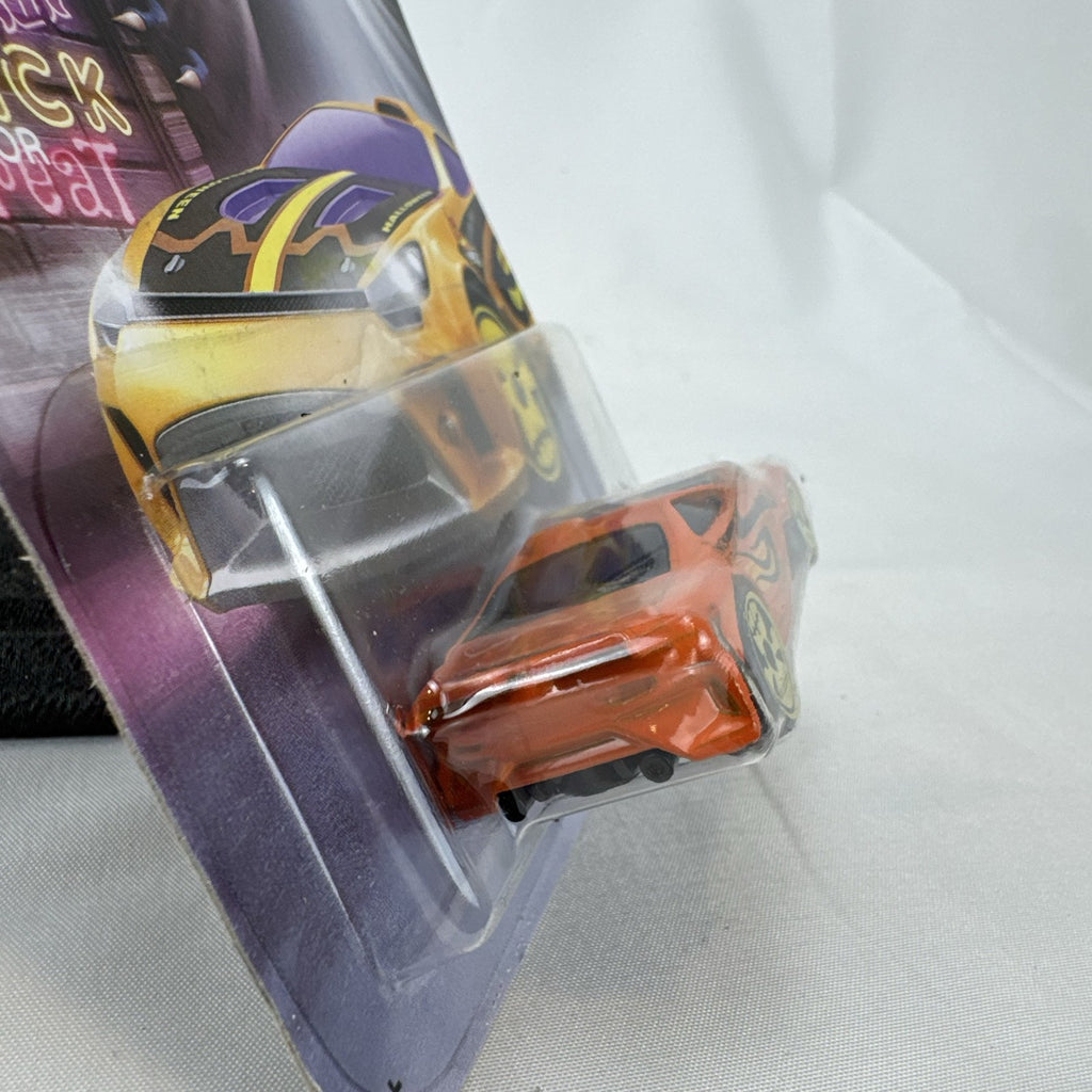 Hot Wheels 1:64 scale Scorcher diecast car in orange with Halloween graphics and yellow skull rims in sealed packaging.