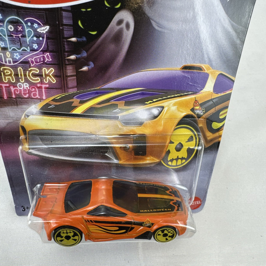 Hot Wheels 1:64 scale Scorcher diecast car in orange with Halloween graphics and yellow skull rims in sealed packaging.