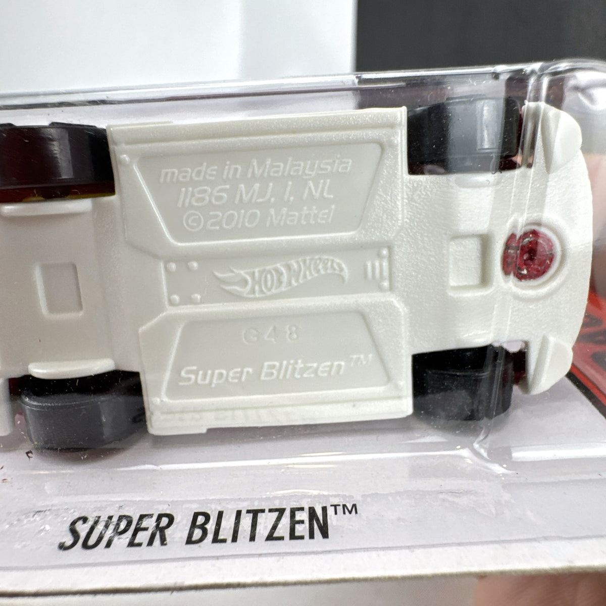 Hot Wheels Super Blitzen diecast car in red with yellow racing stripes and yellow spoiler in original blister package.