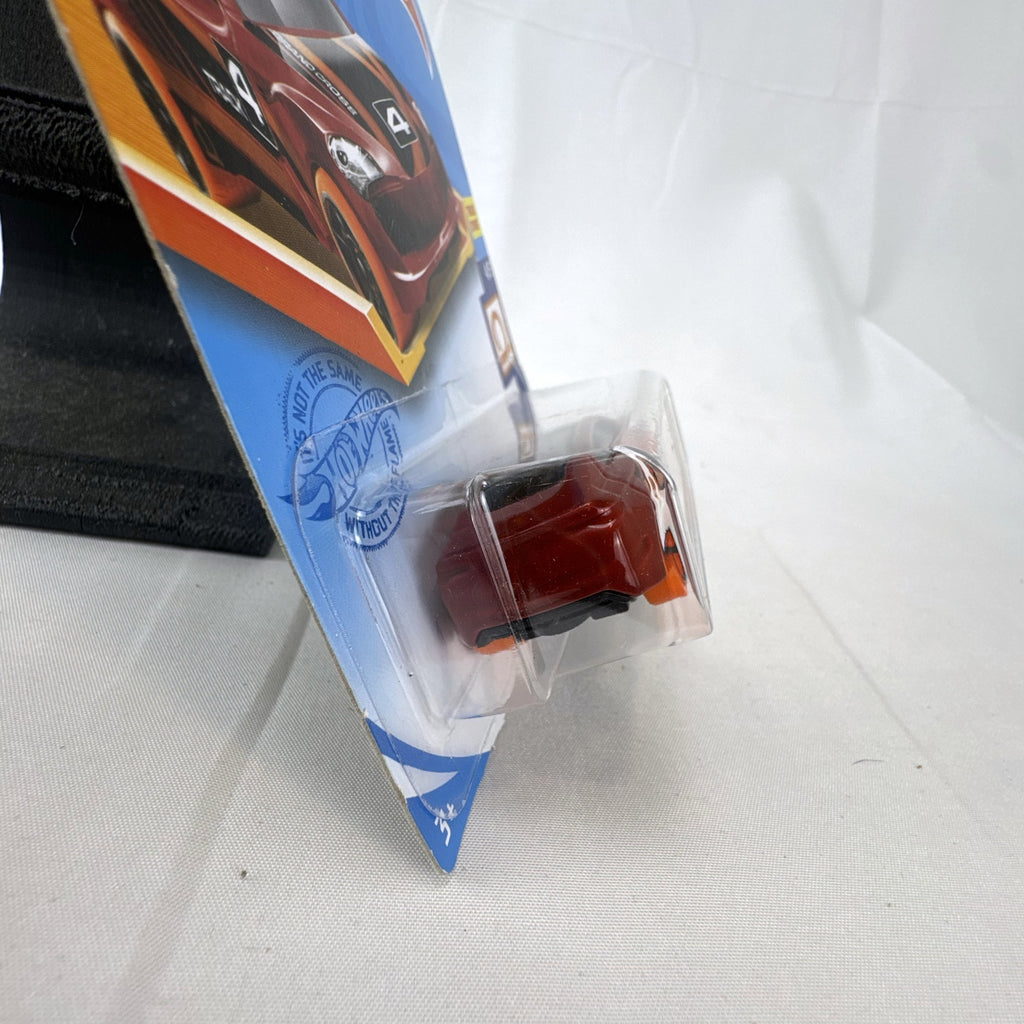 Hot Wheels Track Stars Grand Cross diecast racer in metallic red with orange wheels, sealed on card.