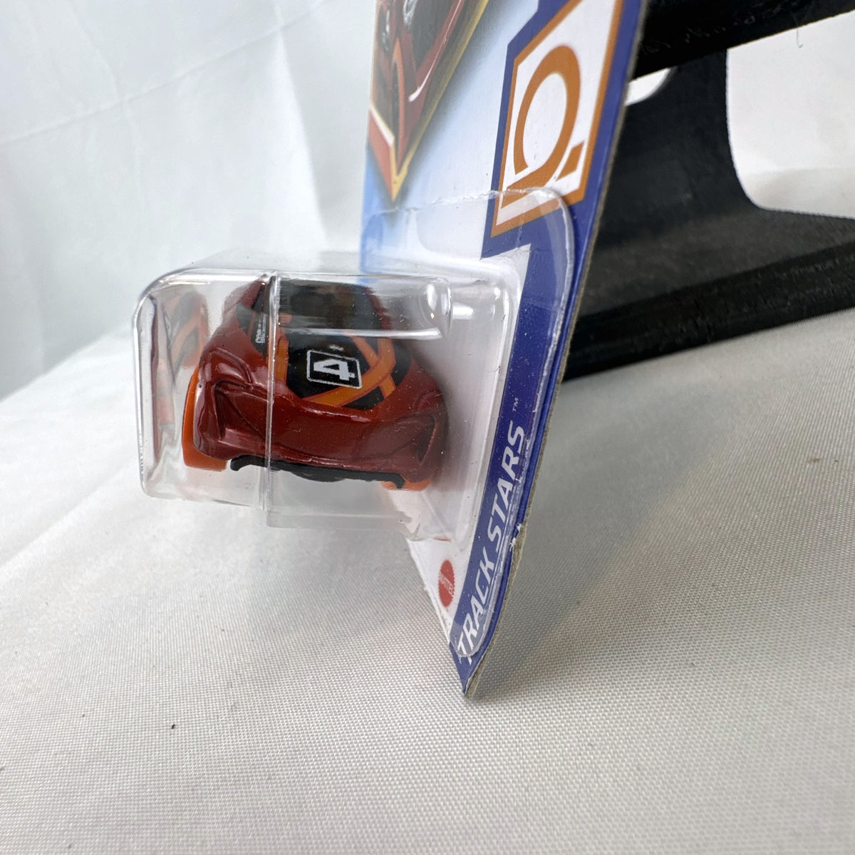 Sealed 1:64 scale Hot Wheels Grand Cross diecast car in metallic red with orange wheels and track stars graphics.