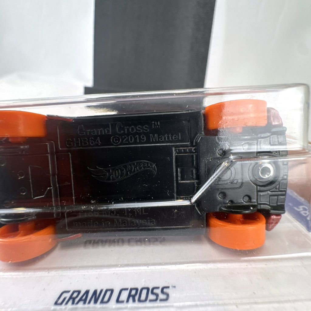 Sealed 1:64 scale Hot Wheels Grand Cross diecast car in metallic red with orange wheels and track stars graphics.