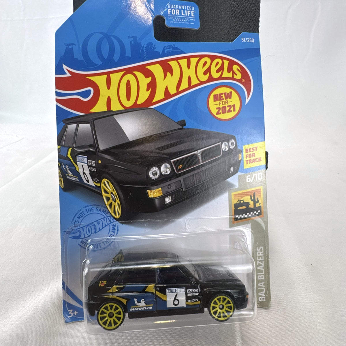 Hot Wheels 1:64 scale 1994 Lancia Delta Integrale diecast rally car in black with yellow wheels, sealed in package