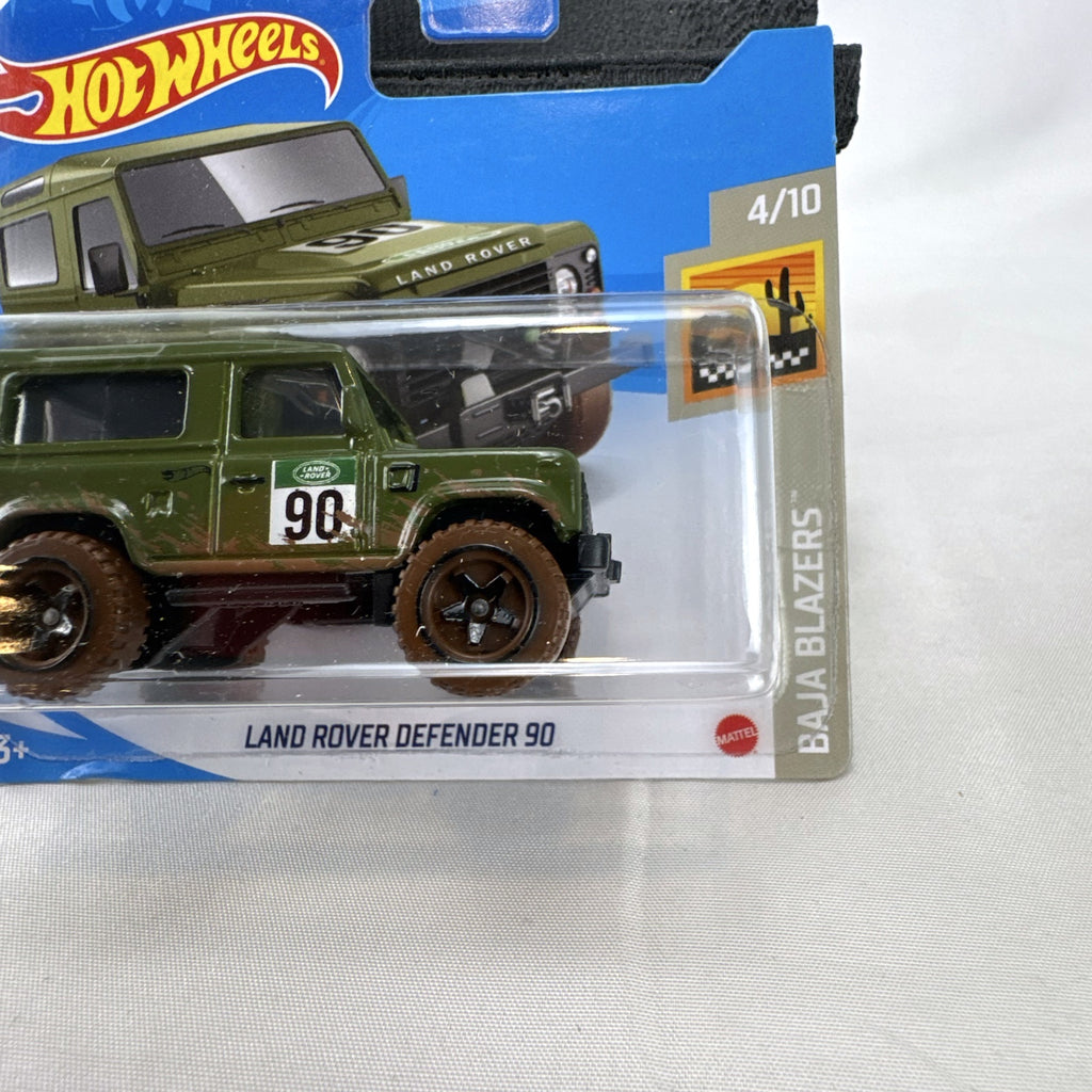 Hot Wheels 1:64 scale Land Rover Defender 90 diecast SUV in olive green with mud splatter on card