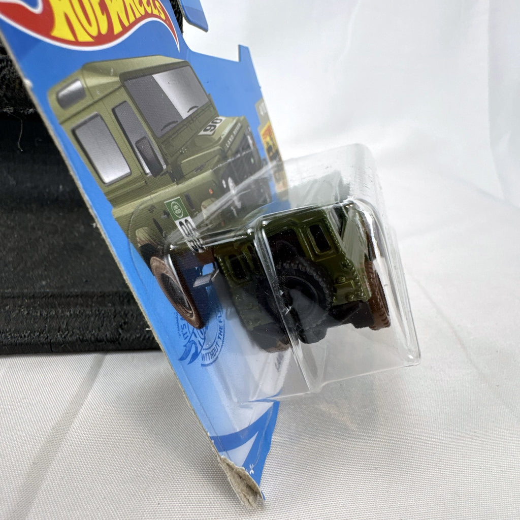 Hot Wheels 1:64 scale Land Rover Defender 90 diecast SUV in olive green with mud splatter on card