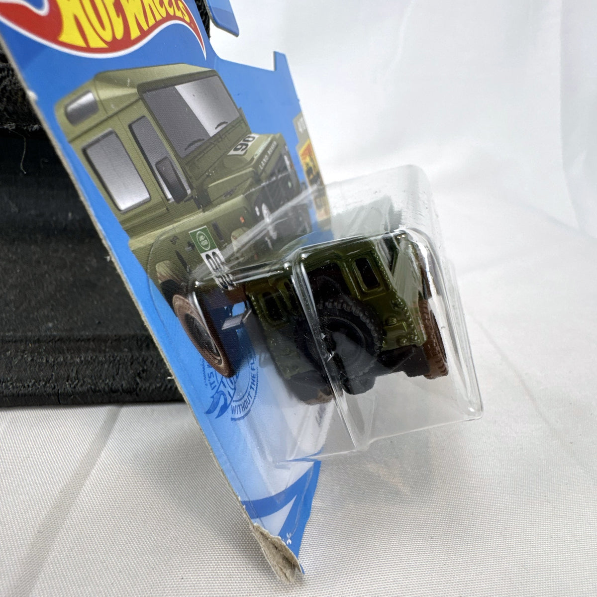 Hot Wheels 1:64 scale Land Rover Defender 90 diecast SUV in olive green with mud splatter on card