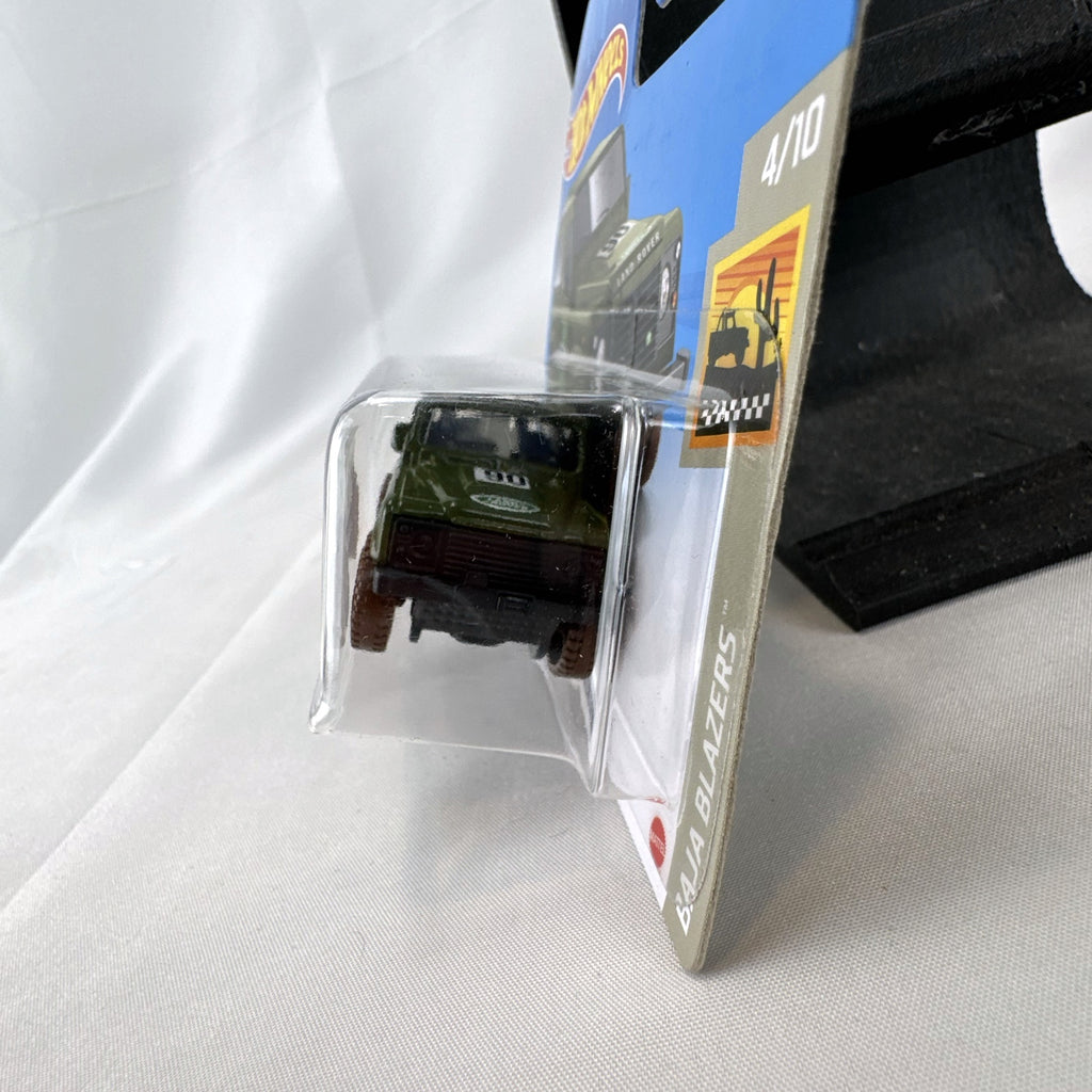 Hot Wheels 1:64 scale Land Rover Defender 90 diecast SUV in olive green with mud splatter on card