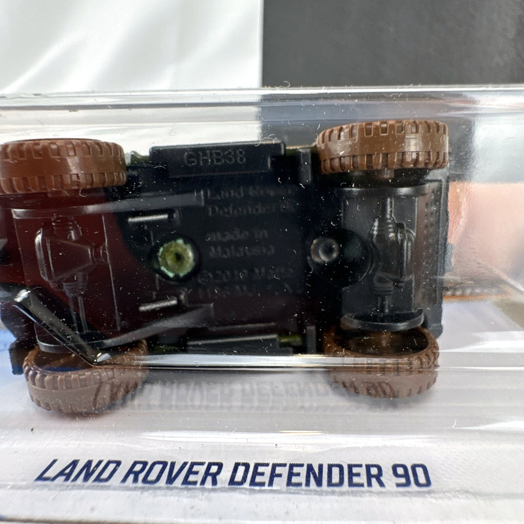 Hot Wheels 1:64 scale Land Rover Defender 90 diecast SUV in olive green with mud splatter on card