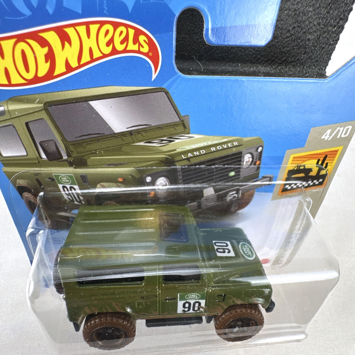 Hot Wheels 1:64 scale Land Rover Defender 90 diecast SUV in olive green with mud splatter on card