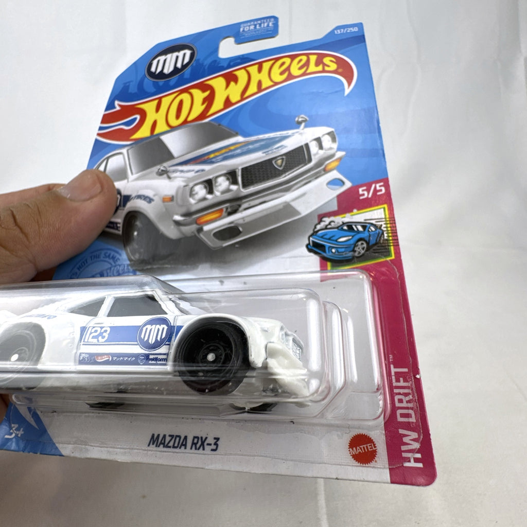 White Hot Wheels 1:64 scale Mazda RX-3 diecast car in Mad Mike HW Drift livery sealed on card.