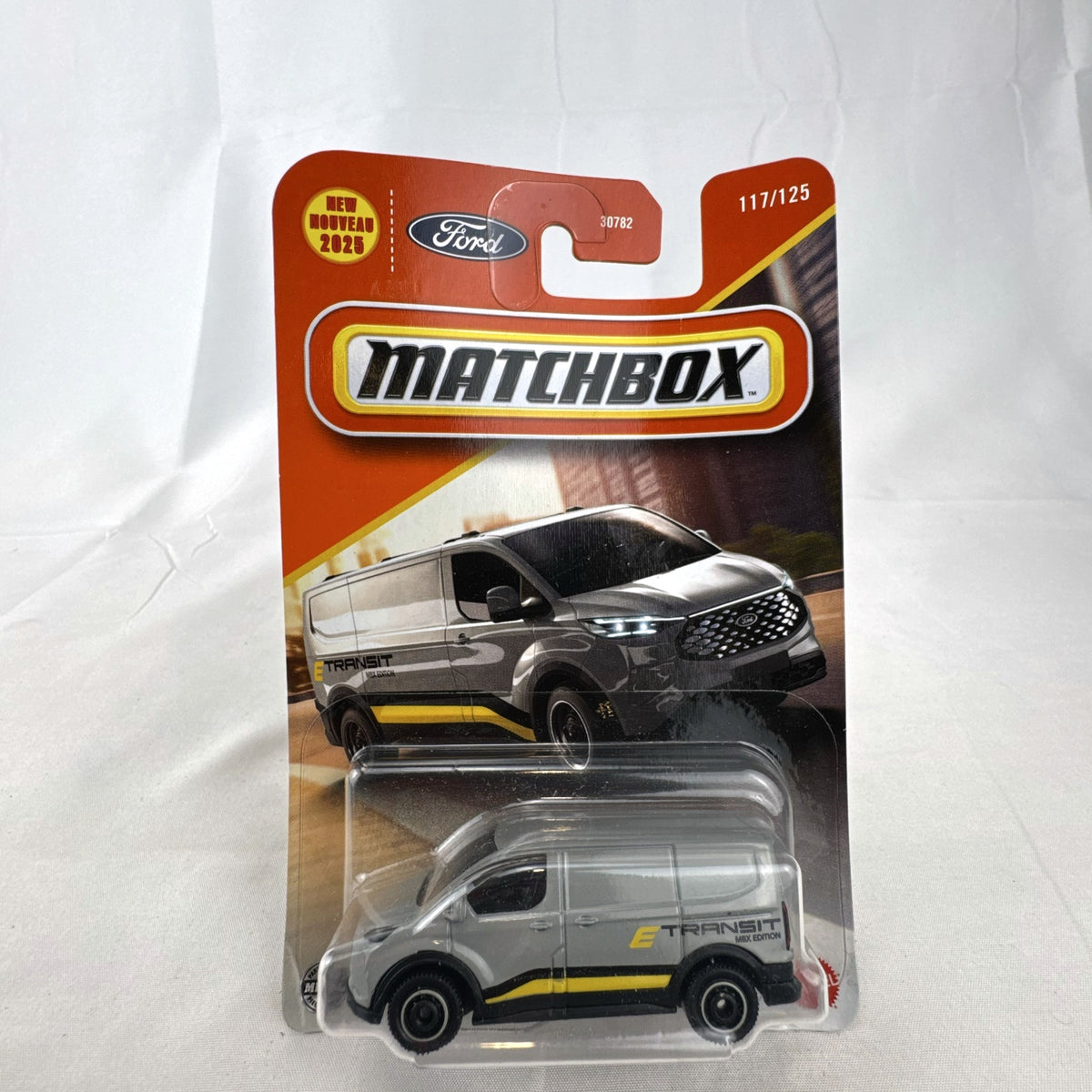 Matchbox 2023 Ford E-Transit Custom diecast van in gray with MBX Edition livery, sealed on card.