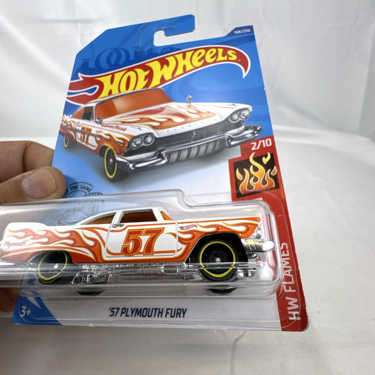 Hot Wheels 1:64 scale '57 Plymouth Fury diecast car in white with HW Flames graphics in original sealed packaging.