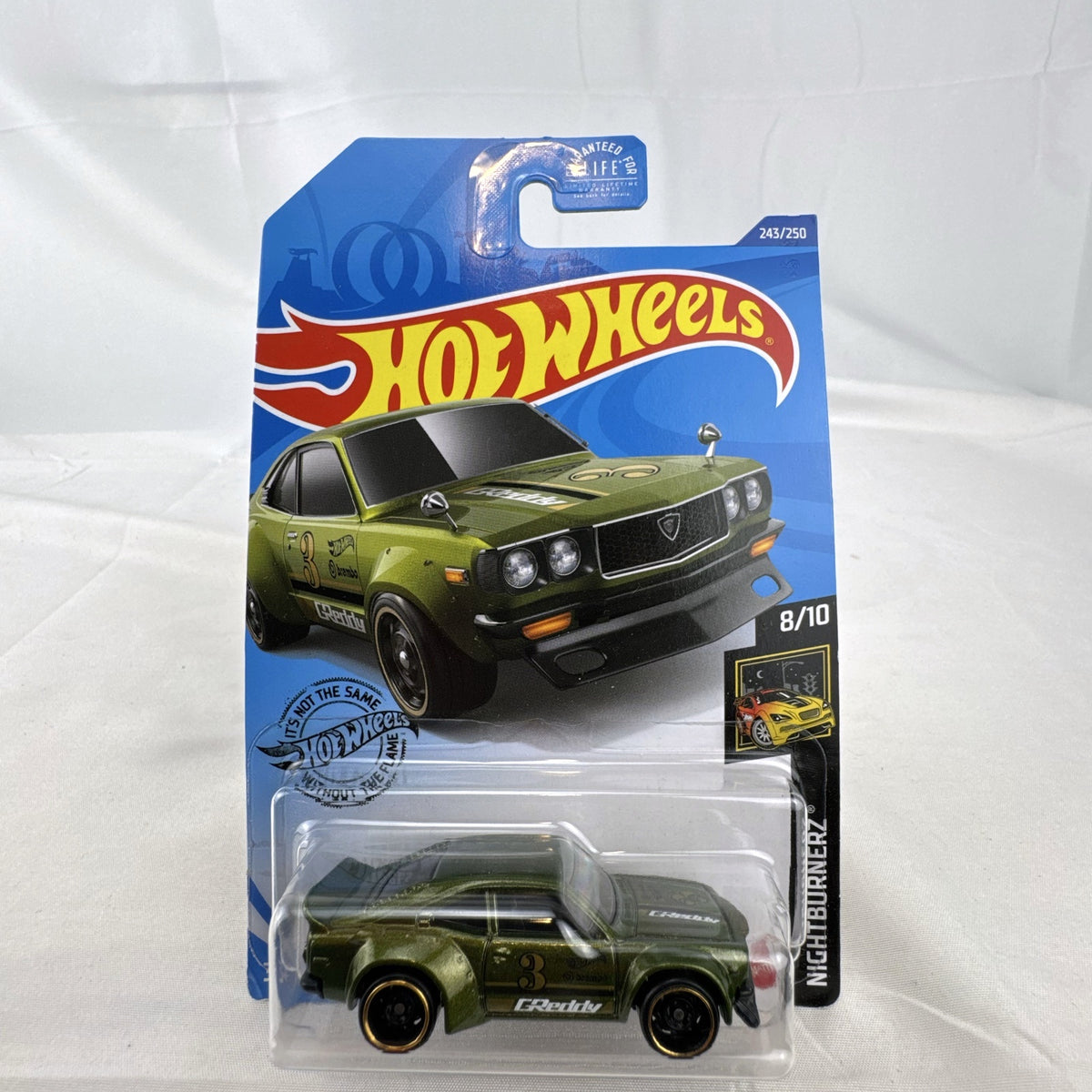 Hot Wheels 1:64 scale Mazda RX-3 diecast car in metallic olive green with GReddy graphics on blister card