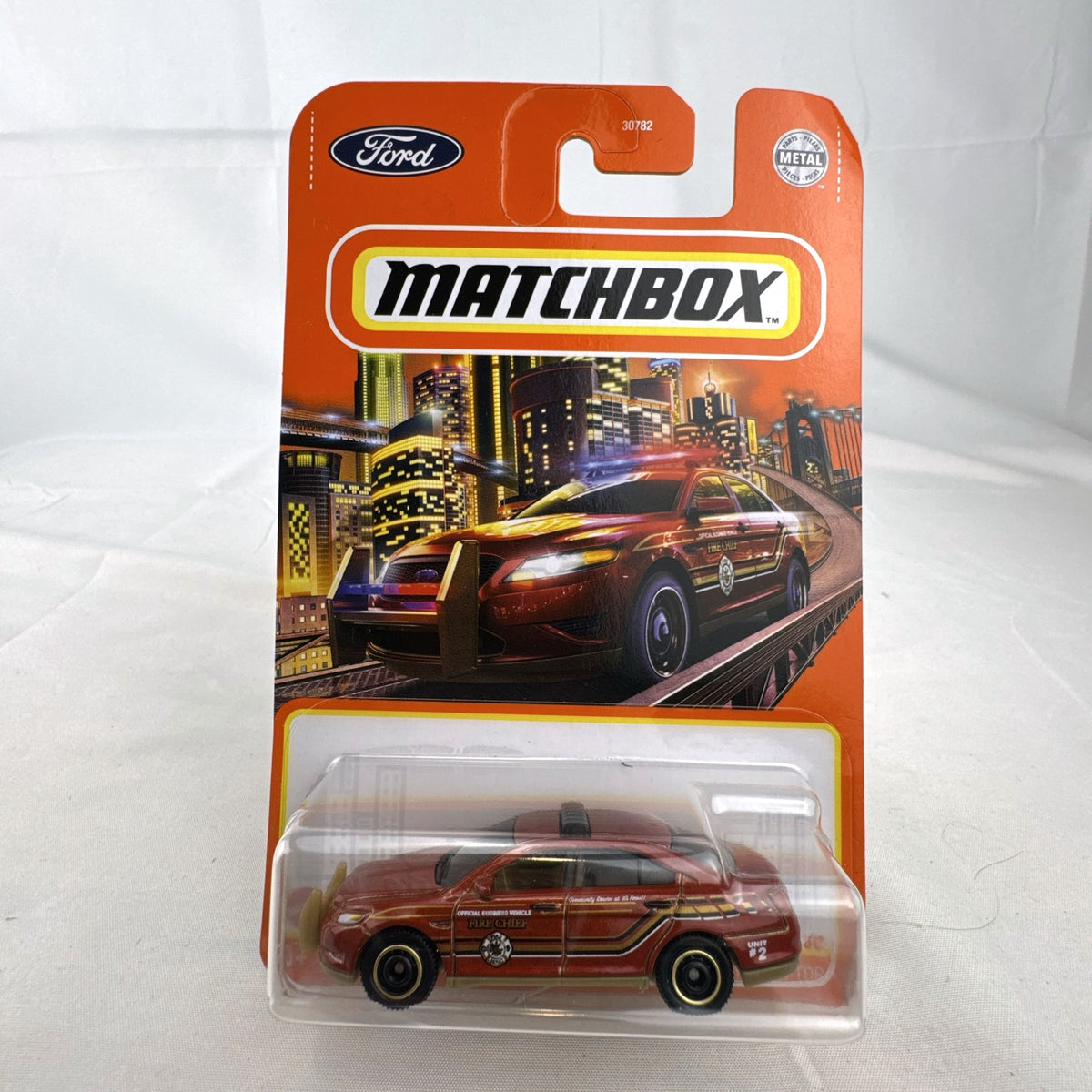 Matchbox 1:64 scale Ford Police Interceptor Fire Chief diecast car in original red packaging with gold push bumper.