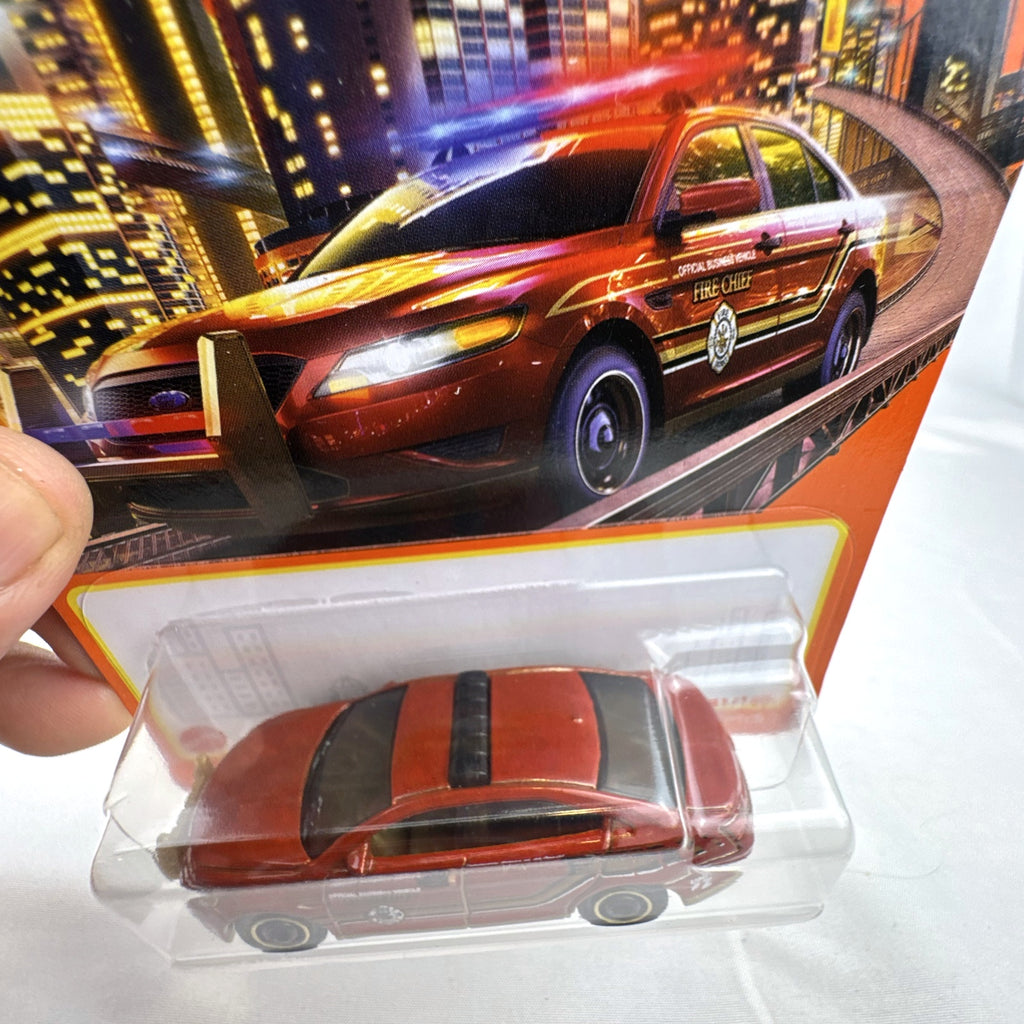 Matchbox 1:64 scale Ford Police Interceptor Fire Chief diecast car in original red packaging with gold push bumper.