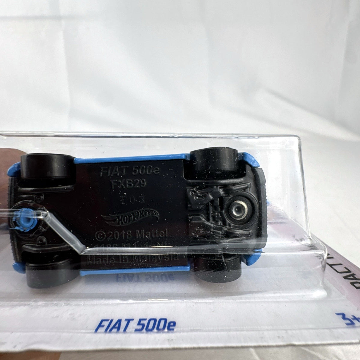 Hot Wheels 1:64 scale diecast Fiat 500e in light blue with racing graphics, sealed on card.