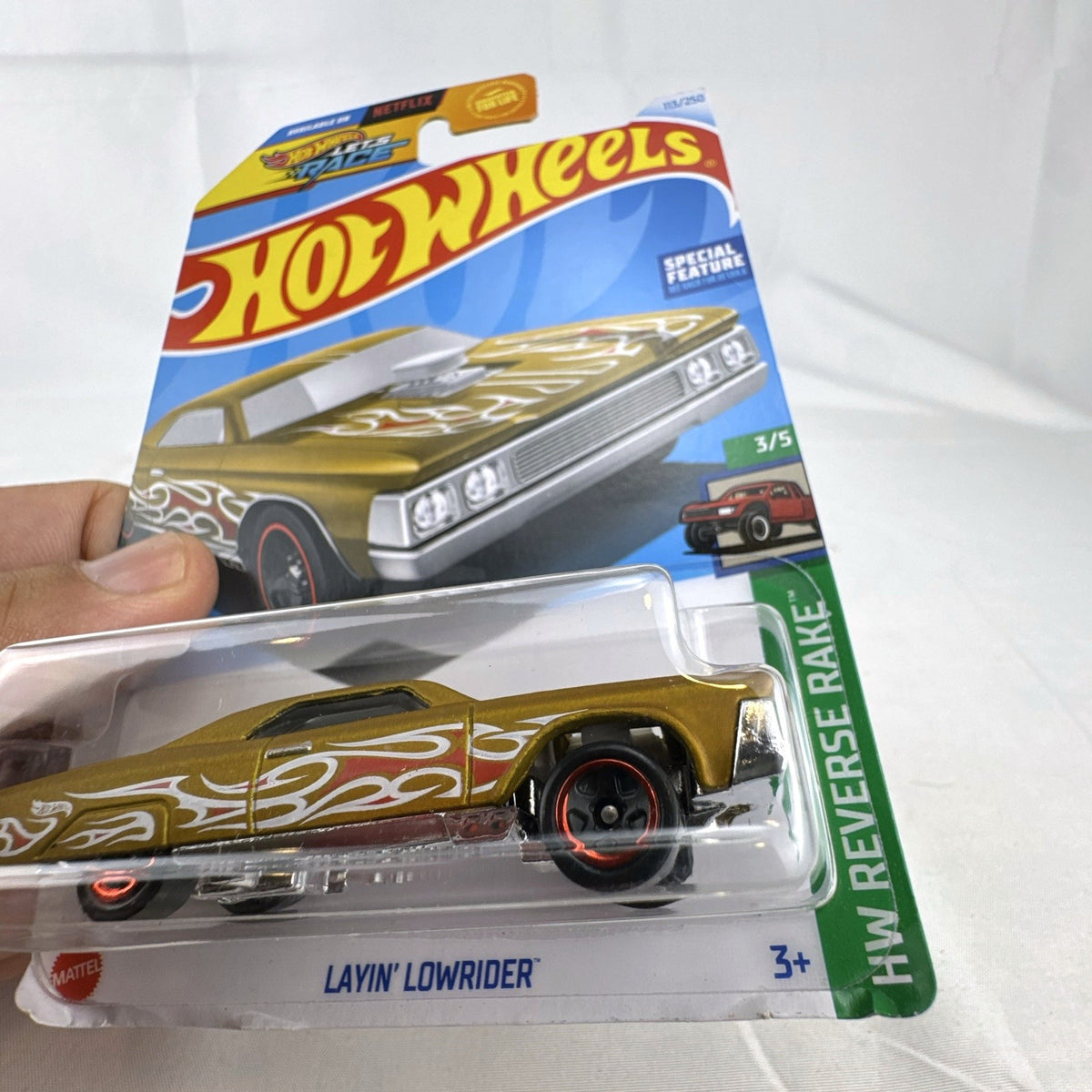 Hot Wheels 1:64 scale Layin' Lowrider diecast car in gold with red and white flame tampos in original carded packaging