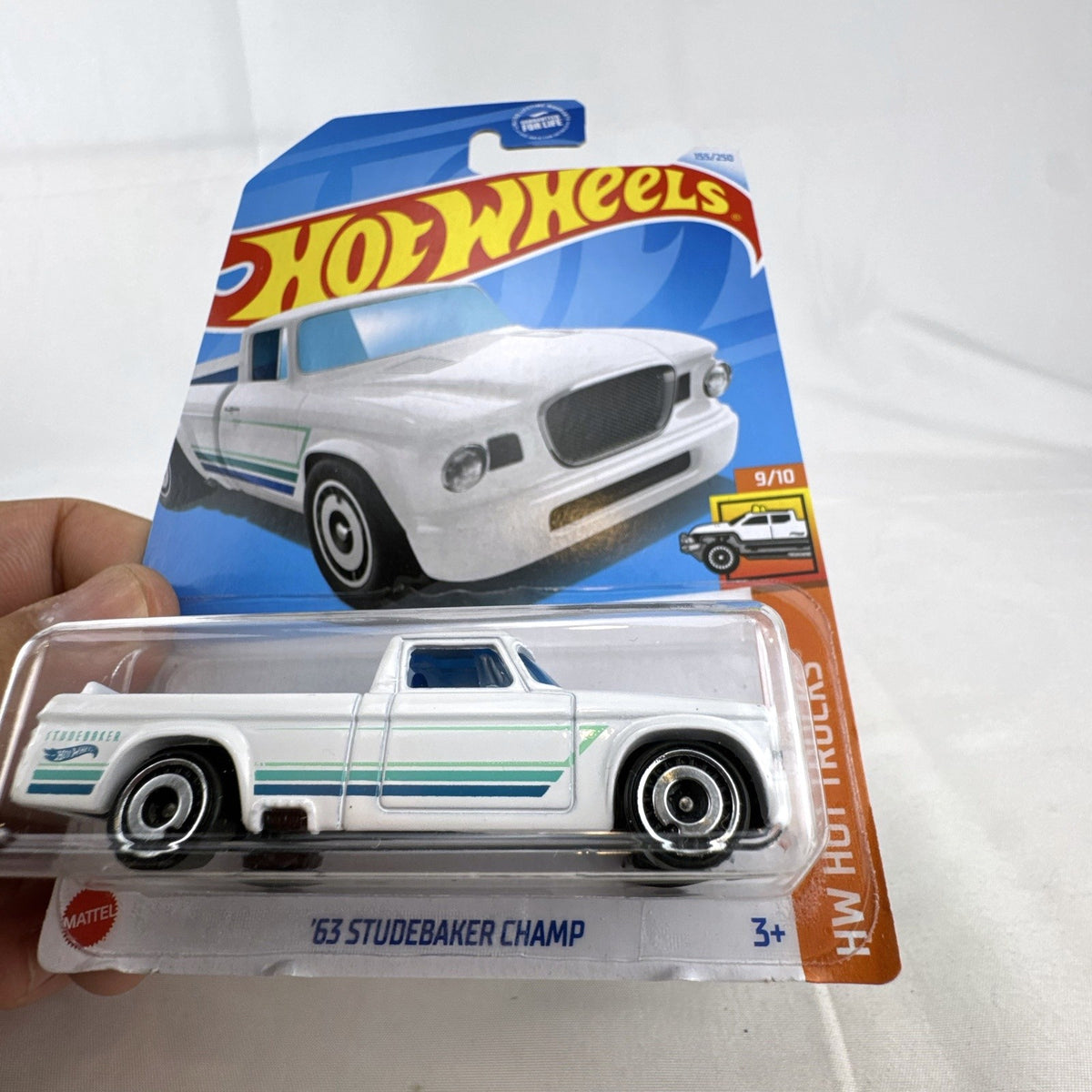 Hot Wheels 1:64 scale 1963 Studebaker Champ pickup truck in white with teal side graphics, sealed in original package.